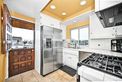 a kitchen with a stainless steel refrigerator and white cabinets at Spanish Castle By The Sea in Newport Beach in Newport Beach