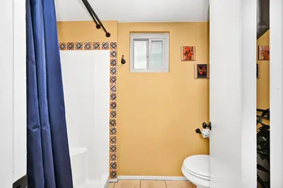 a bathroom with a toilet and a blue shower curtain at Spanish Castle By The Sea in Newport Beach in Newport Beach