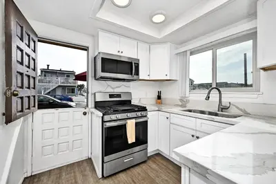 a white kitchen with a stove and a microwave at Charming 1-Bedroom Home on 29th Street in Newport Beach
