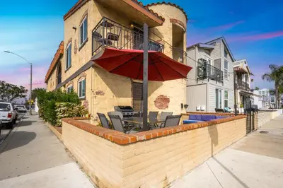 a building with a patio with an umbrella and chairs at Charming 1-Bedroom Home on 29th Street in Newport Beach
