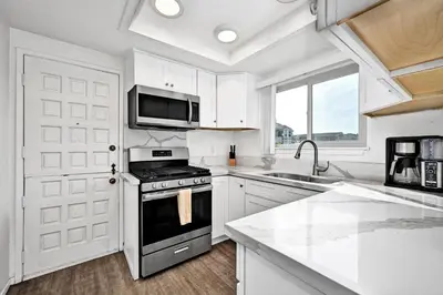 a white kitchen with a stove and a microwave at Spanish Castle in Newport Steps to the Sand and Grocery Store in Newport Beach