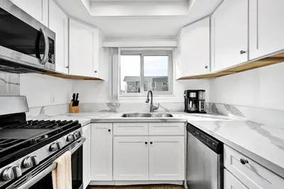 a white kitchen with a sink and a stove at Spanish Castle in Newport Steps to the Sand and Grocery Store in Newport Beach