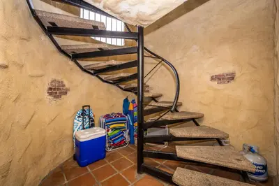 a spiral staircase in a room with surfboards at Spanish Castle in Newport Steps to the Sand and Grocery Store in Newport Beach