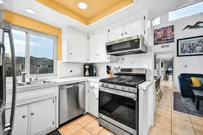 a kitchen with white cabinets and a stove top oven at Spanish Castle in Newport Steps to the Sand and Grocery Store in Newport Beach