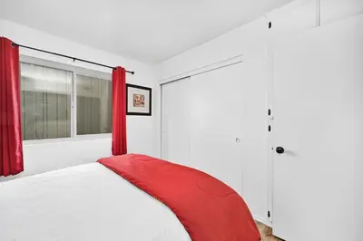 a bedroom with a bed with red curtains at Spanish Castle in Newport Steps to the Sand and Grocery Store in Newport Beach