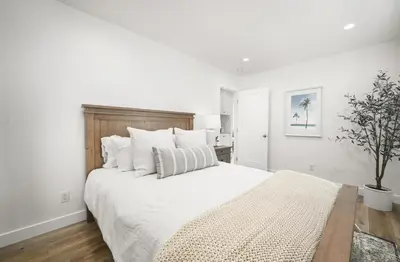 a white bedroom with a large bed with white pillows at Remodeled - Modern - 2 Bedroom - Walk to the Beach in Newport Beach