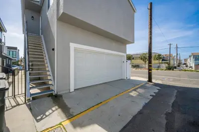 a building with a white garage door and stairs at Remodeled - Modern - 2 Bedroom - Walk to the Beach in Newport Beach