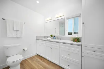 a white bathroom with a toilet and a sink at Remodeled - Modern - 2 Bedroom - Walk to the Beach in Newport Beach
