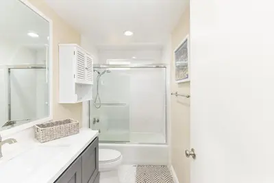 a white bathroom with a shower and a toilet at 2 Bed 2 Bath Jacuzzi Home with Parking on 51st St in Newport Beach