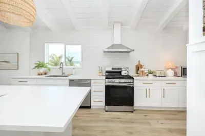 a kitchen with white cabinets and a black stove at Great Location near the Balboa Pier and Fun Zone with Air conditioning in Newport Beach