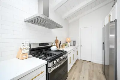a white kitchen with a black stove top oven at Great Location near the Balboa Pier and Fun Zone with Air conditioning in Newport Beach