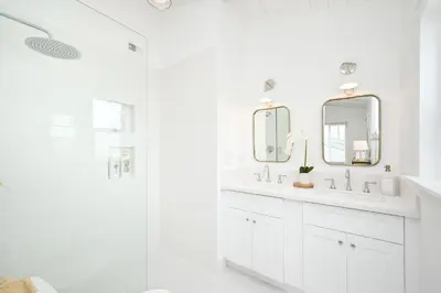 a white bathroom with two sinks and a shower at Great Location near the Balboa Pier and Fun Zone with Air conditioning in Newport Beach