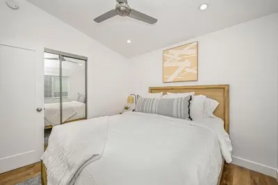 a white bedroom with a bed and a ceiling fan at Remodeled Beach Home with 2 Car Parking Patio and Firepit in Newport Beach