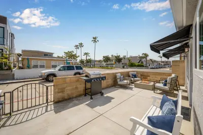 a patio with chairs and a grill on a balcony at Remodeled Beach Home with 2 Car Parking Patio and Firepit in Newport Beach