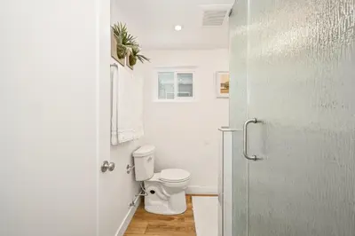 a white bathroom with a toilet and a door at Remodeled Beach Home with 2 Car Parking Patio and Firepit in Newport Beach
