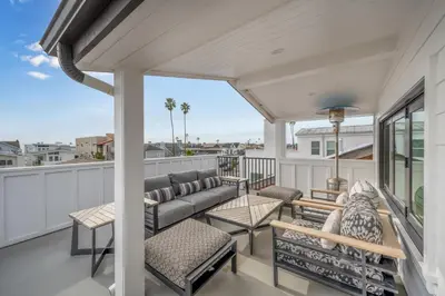 a patio with a couch and chairs on a balcony at 4 Bedrooms in BRAND NEW Luxury built Home walk to the beach in Newport Beach