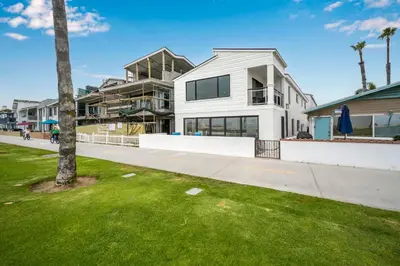 a white house with a palm tree in front of it at 3 Bedroom with Park and Beach in your Backyard! in Newport Beach