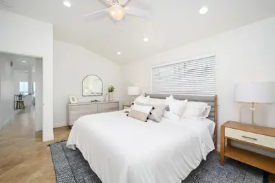 a white bedroom with a large bed and a ceiling fan at 3 Bedroom with Park and Beach in your Backyard! in Newport Beach