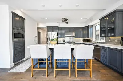 a kitchen with black cabinets and white counter tops at Upscale Home with Rooftop Deck, Jacuzzi, & Firepit in Newport Beach