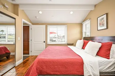 a bedroom with a large bed with red and white pillows at 50 Steps to the Sand on 39th St - Newport Beach in Newport Beach