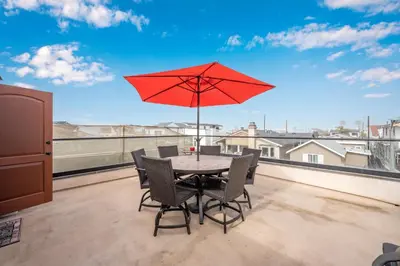 a table and chairs with a red umbrella on a balcony at 50 Steps to the Sand on 39th St - Newport Beach in Newport Beach