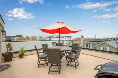 a patio with a table and chairs and an umbrella at 50 Steps to the Sand on 39th St - Newport Beach in Newport Beach