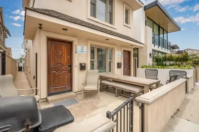 a patio with a wooden bench and a wooden door at Modern Beach House Steps from the Sand on 39th St in Newport Beach