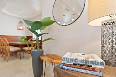 a table with a stack of books and a mirror at Modern Beach House Steps from the Sand on 39th St in Newport Beach