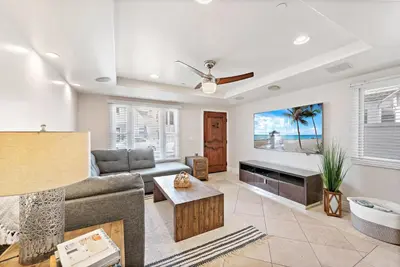 a living room with a couch and a tv at Modern Beach House Steps from the Sand on 39th St in Newport Beach
