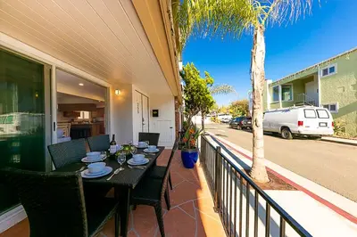 a table and chairs on a balcony with a palm tree at 2 Story Home with Garage 1 Block to the Beach wi in Newport Beach