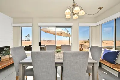 a dining room with a table with chairs and an umbrella at Oceanfront Home on the Boardwalk with 3 car Garage, AC, Giant Patio, Ocean Views, Walk to Pier in Newport Beach