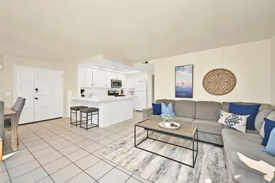 a living room with a couch and a table at Oceanfront Home on the Boardwalk with 3 car Garage, AC, Giant Patio, Ocean Views, Walk to Pier in Newport Beach