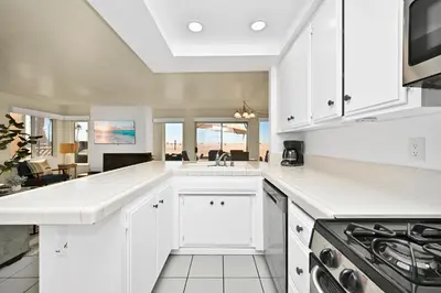 a kitchen with white cabinets and a view of the ocean at Oceanfront Home on the Boardwalk with 3 car Garage, AC, Giant Patio, Ocean Views, Walk to Pier in Newport Beach