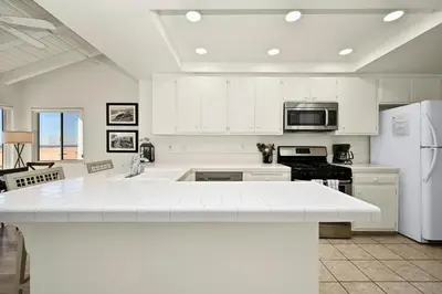 a kitchen with white cabinets and a white counter top at Oceanfront Home on the Boardwalk with 3 car Garage, AC, Giant Patio, Ocean Views, Walk to Pier in Newport Beach