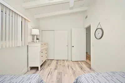 a bedroom with a bed and a dresser and a clock at Oceanfront Home on the Boardwalk with 3 car Garage, AC, Giant Patio, Ocean Views, Walk to Pier in Newport Beach