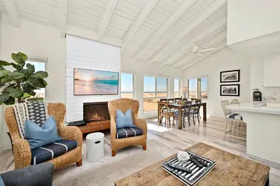 a living room with two chairs and a table at Oceanfront Home on the Boardwalk with 3 car Garage, AC, Giant Patio, Ocean Views, Walk to Pier in Newport Beach