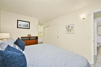 a white bedroom with a bed and a desk at Oceanfront Home on the Boardwalk with 3 car Garage, AC, Giant Patio, Ocean Views, Walk to Pier in Newport Beach