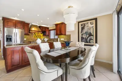 a kitchen with a dining room table and white chairs at 7 Bedroom Oceanfront Triplex Building in Newport Beach