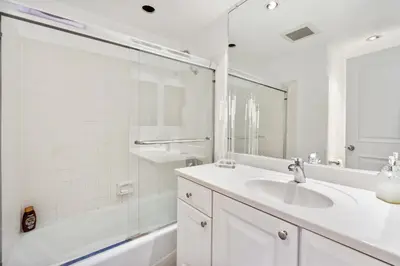 a white bathroom with a sink and a shower at 2 Bed 2 Bath BACK APT Steps to the Sand in Newport Beach