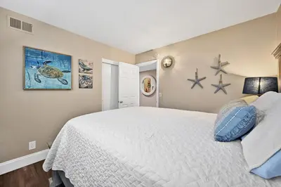 a bedroom with a white bed with blue pillows at Giant Beachfront Home with Parking near the Pier in Newport Beach
