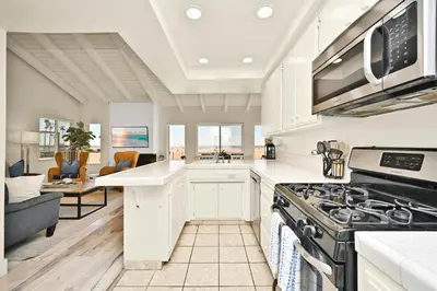 a kitchen with white cabinets and a stove top oven at Beachfront home with Sweeping Ocean Views, AC, Walk to the Pier, Restaurants, Shops, Activities in Newport Beach