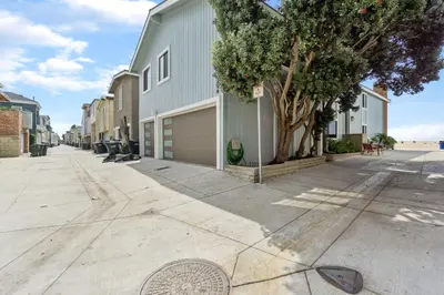a street with a building and a tree next to a sidewalk at 2 Homes Rented Together on the Oceanfront in Newport Beach