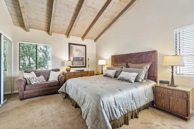 a bedroom with a large bed and a chair at 2 Homes Rented Together on the Oceanfront in Newport Beach