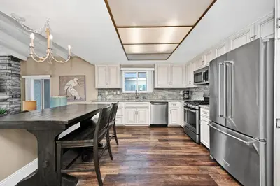 a kitchen with white cabinets and a table and a refrigerator at Stunning Oceanfront Retreat in Newport Beach in Newport Beach