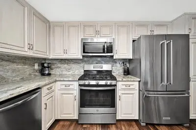 a kitchen with white cabinets and stainless steel appliances at Stunning Oceanfront Retreat in Newport Beach in Newport Beach