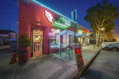 a red building with tables and umbrellas on a street at Ocean View Blue Mission Beach Paradise in San Diego