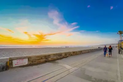 two people walking along the beach at sunset at Ocean View Blue Mission Beach Paradise in San Diego