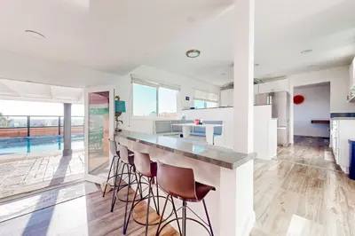 a kitchen with white walls and a bar with stools at Dog-Friendly Home Saltwater Pool, Fire Pit, Games in San Diego