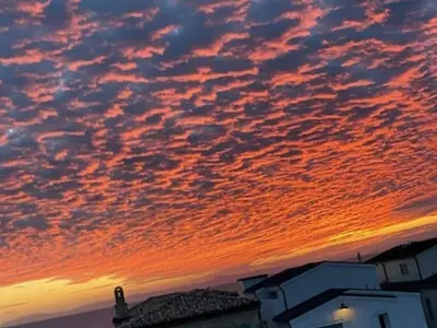 a sunset with clouds in the sky over a building at Newport Beach House in Newport Beach