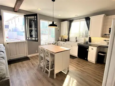 a kitchen with white cabinets and a table in it at Newport Beach House in Newport Beach